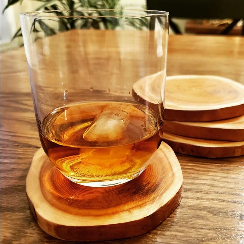 Glass of bourbon on a set of yule-log wood slice coasters