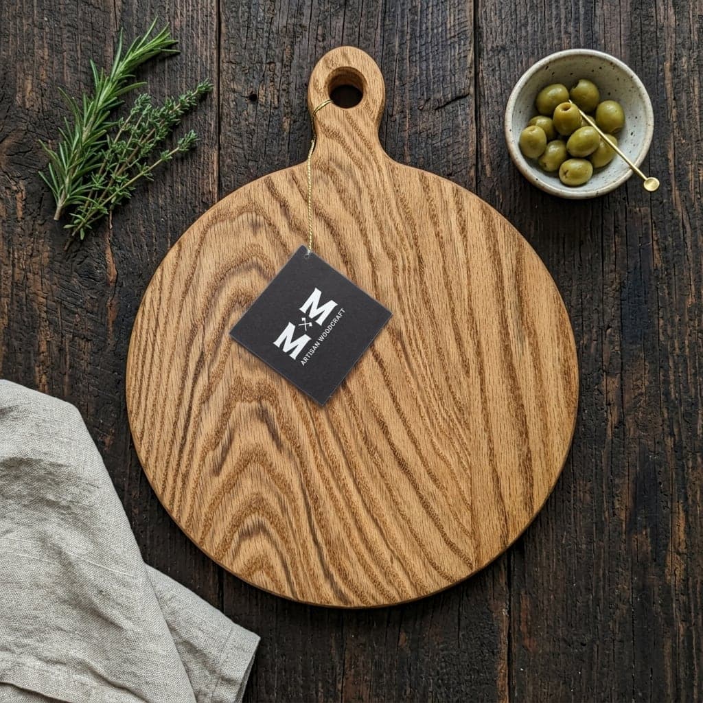 Red Oak Avalon round charcuterie board with a handle and Moose Mill tag on a dark rustic table