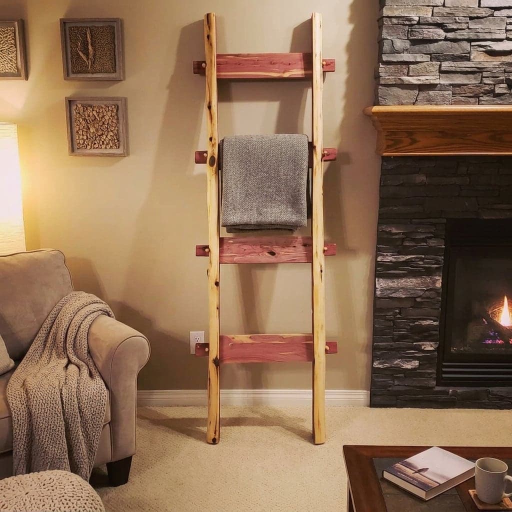 Cedar Blanket Ladder with natural log rails and red cedar rungs, holding a grey throw beside a fireplace